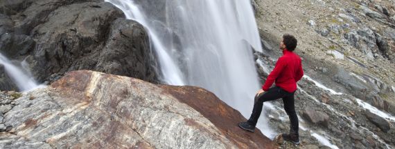 Un uomo guarda una cascata in montagna